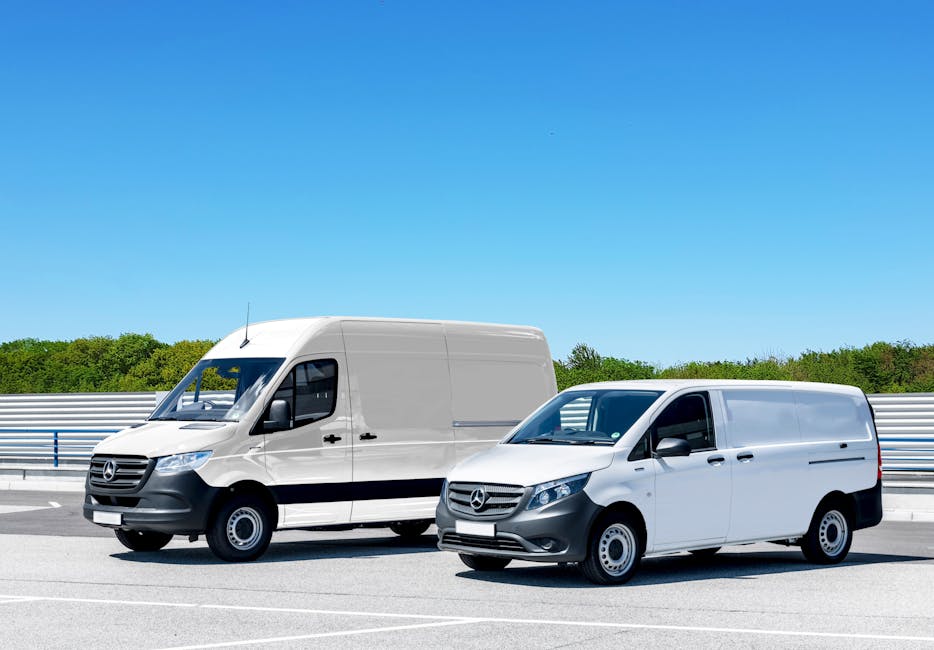 A black Mercedes-Benz van parked on a city street, surrounded by multi-storey limestone and brick buildings with large windows, during daytime with clear sky. The van is positioned near the curb on a
